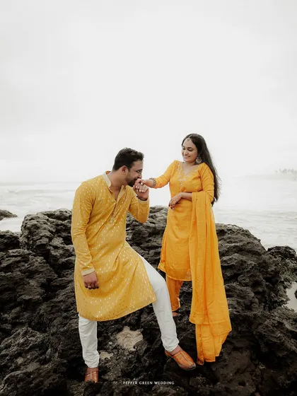 A groom-to-be kisses his partner's hand, a classic gesture of romance captured during their beach pre-wedding shoot.