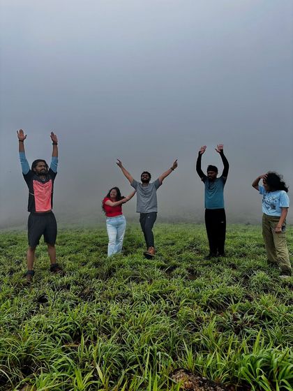 A group of friends celebrating at the top of Gangadikal, with the mist all around them.