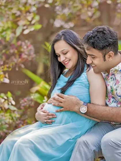 This is a perfect example of a relaxed, outdoor couple's portrait. The soft, diffused light through the trees creates a romantic atmosphere as they share a happy moment together.