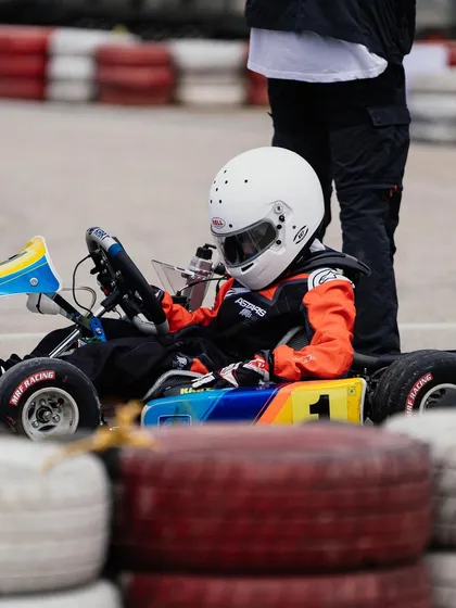 A young driver waits by his kart.