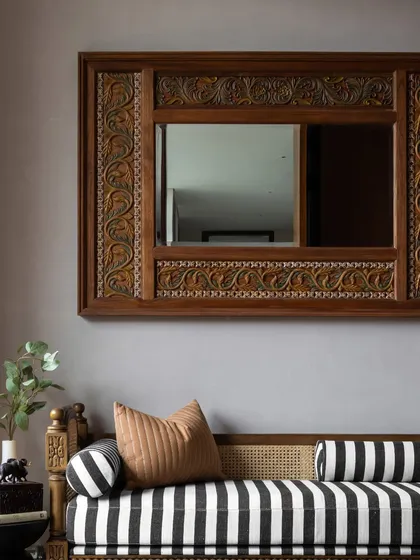 A bold, striped daybed is paired with an antique carved mirror in this bedroom, creating a playful yet sophisticated contrast. This is how we layer different styles to tell a unique story.