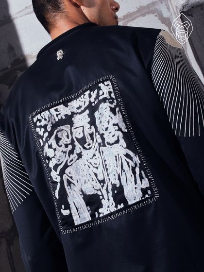 The back of the Stellar Jacket, featuring a unique graphic patch and linear embroidery. This piece is a narrative of discovery, told through texture and form.