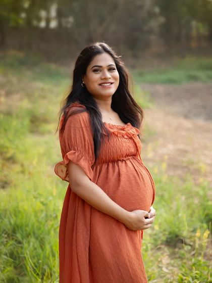 A simple, beautiful solo portrait of the mother-to-be in a sunlit field. Her gentle smile and the soft light create a warm and serene image.