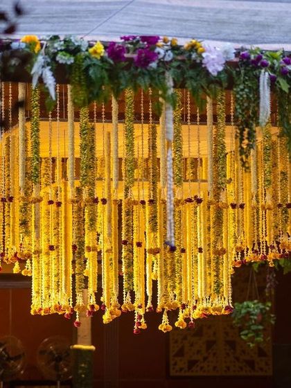 A stunning hanging floral chandelier made of marigolds and tuberoses, serving as the centerpiece of the mandap for a traditional wedding.