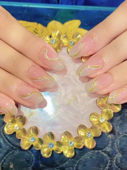A delicate and elegant design with sheer nude nails adorned with fine, wavy gold glitter lines.