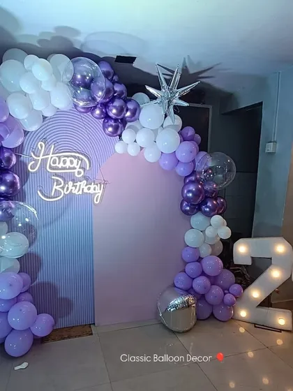 A full view of the 24th birthday decor, showcasing the asymmetrical balloon arch against the ribbed pastel backdrop. We provide a small pedestal for the cake to complete the photo-ready setup.