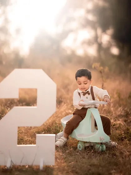 An outdoor second birthday shoot with a large number prop and a toy car. I can take the celebration outside for a different look and feel.