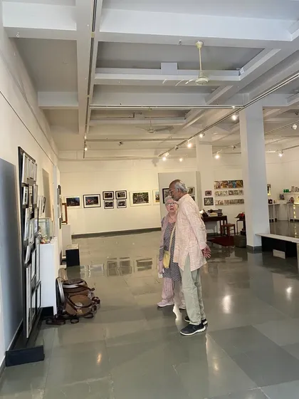 A wide shot of artist Balan Nambiar and his companion walking through the gallery.