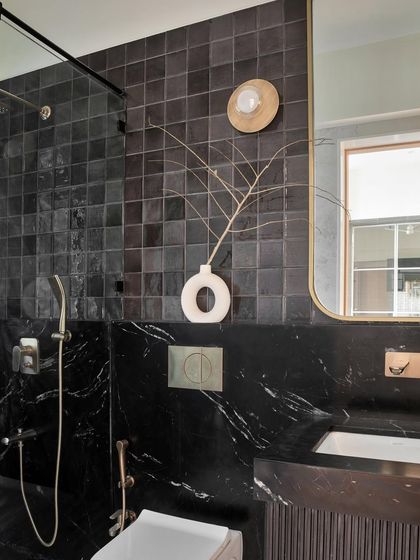 The study bathroom features dramatic black square tiles and Brazilian black marble, creating a dark and moody atmosphere. The design is a personal favorite for its bold and sophisticated look.