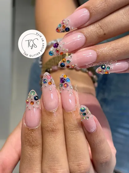 A full view of these long, stiletto-shaped nails with a beautiful gradient of colorful rhinestones at the tips.