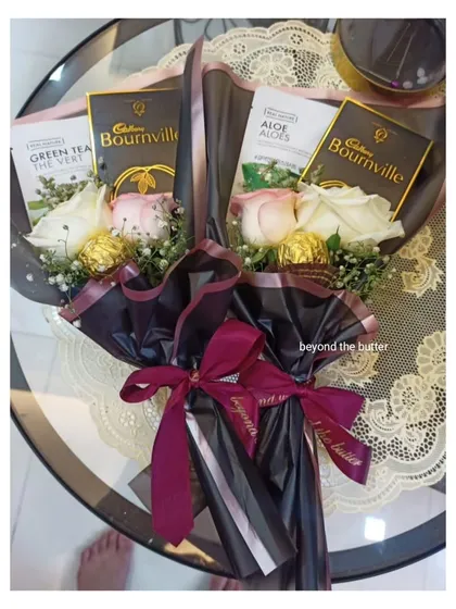 A custom bouquet combining flowers with other treats. This one includes roses, Ferrero Rochers, Green Tea, and Cadbury Bournville chocolate bars.