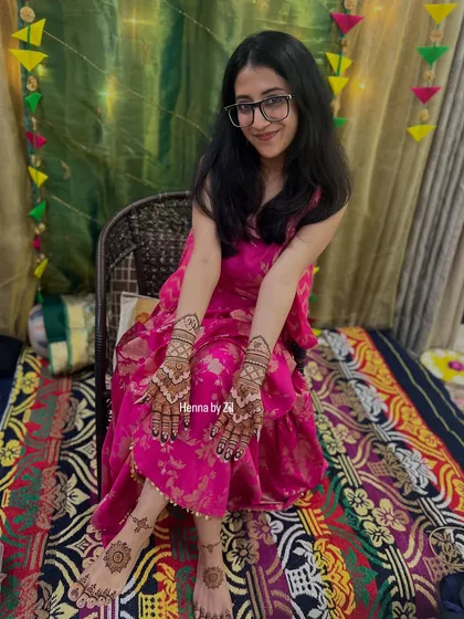 A happy bride showing her complete mehendi look, with beautiful designs on both her hands and feet.
