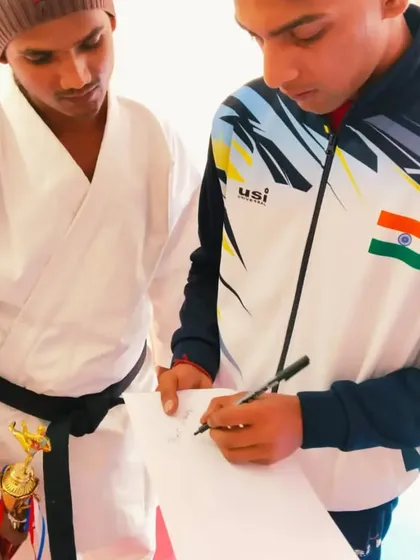 A senior athlete signs an autograph for a junior student after the belt ceremony, inspiring the next generation.