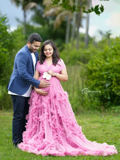 A tender moment between a couple, with the mother-to-be holding tiny baby shoes. Her pink ruffled gown adds a touch of sweetness.