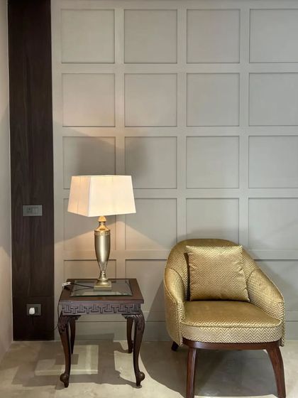 Golden hues and wooden accents merge in this captivating setting. The golden yellow armchair adds warmth, beautifully complementing the geometric textured wall and classic side table.