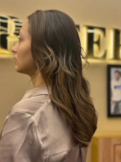 A side profile of a client with her new hair color. The gentle waves and highlights create a look of effortless elegance.