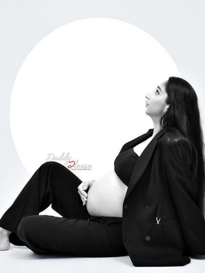 A beautiful black and white profile shot of an expectant mother in a pantsuit. The artistic composition and lighting create a powerful and contemplative mood.