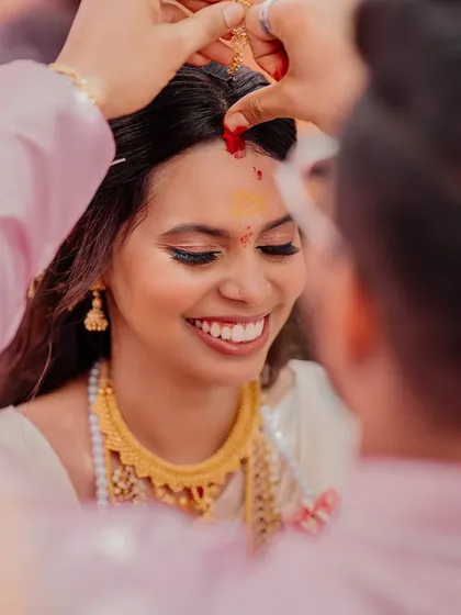 A candid, happy moment during the wedding ceremony. This minimalist look for a South Indian bride focuses on clean skin and a bright smile, proving that less can be more.