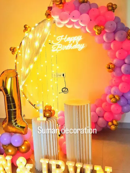 A vibrant first birthday setup for twins, 'Ivan & Irvin'. It features a pink, purple, and gold balloon ring and their names in marquee letters.