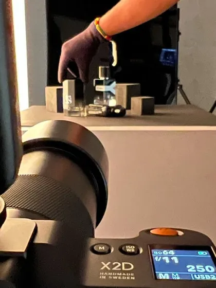 A look through the lens of my Hasselblad X2D during a fragrance shoot. You can see my assistant carefully placing the bottles within the set. This is how we build our compositions, one small adjustment at a time.