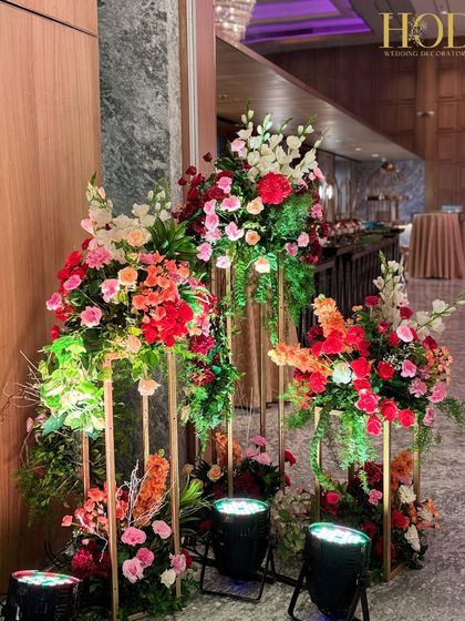 Another view of the tall floral stands, showing how they can be grouped to create a lush, garden-like feel at the entrance of the wedding venue.