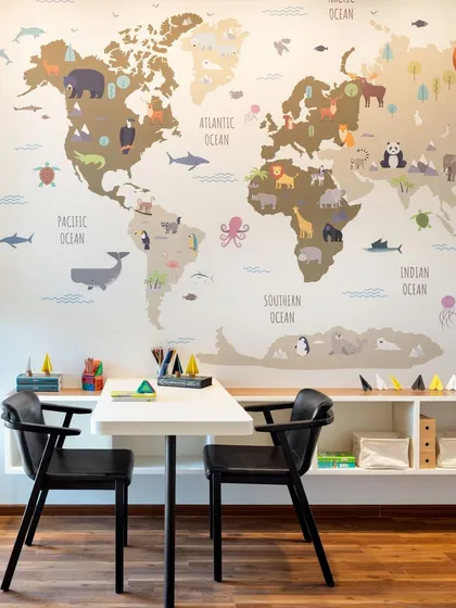 A creative and educational workspace for children, featuring a large world map wall decal. The low table and chairs are perfectly sized for kids, and the open shelving provides easy access to art supplies and books.