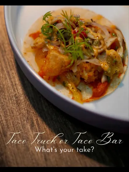 A beautifully plated taco, garnished with fresh herbs, sits on a stylish plate. This image emphasizes the gourmet quality and presentation we bring even to casual, fun food concepts like a taco bar.