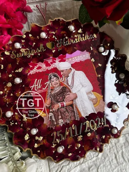 An 8-inch round resin frame with a scalloped edge, featuring a central wedding photo surrounded by preserved deep red rose petals, gold flakes, and pearls.