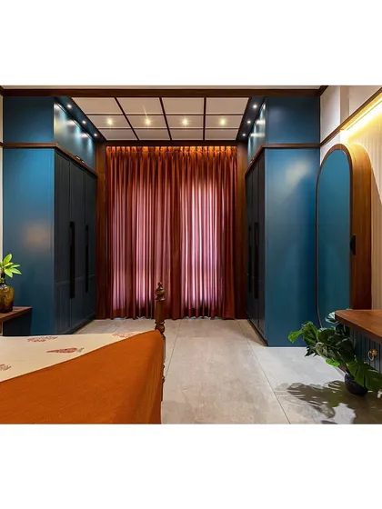 The wardrobe area is designed to maximize storage while adding to the room's aesthetic. The deep blue color provides a bold contrast to the warm wood and neutral walls.