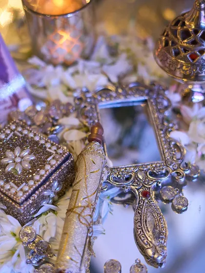 A detail shot of a mirrored surface reflecting an ornate, handheld mirror, a scroll, and a pearl-encrusted box, evoking a sense of old-world romance.