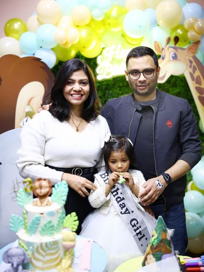 A beautiful family portrait at the cake-cutting ceremony. The safari-themed cake perfectly complements the jungle decor.