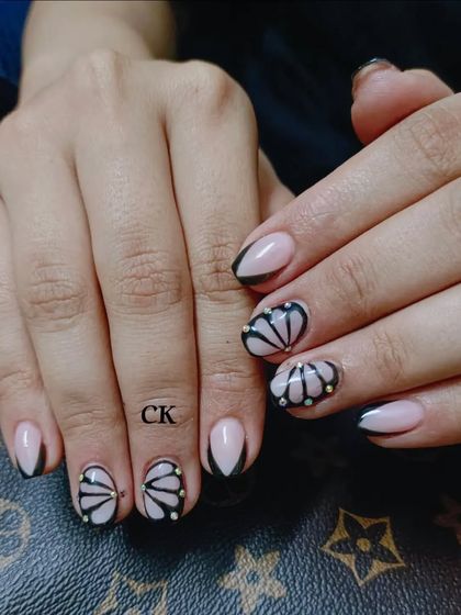 A unique design with a black French tip and a hand-painted shell-like pattern with pearl accents.