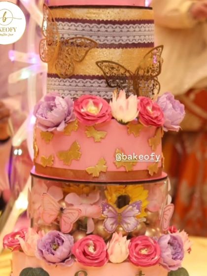 A closer look at the details of the 5-tier twin birthday cake. It features beautiful floral work, golden butterflies, and two acrylic spacers for added height and drama.