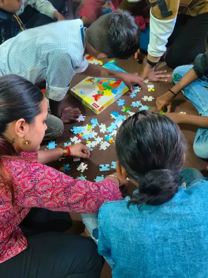 Teamwork makes the dream work. Children and volunteers work together to solve a puzzle, an activity that teaches collaboration, problem-solving, and patience.