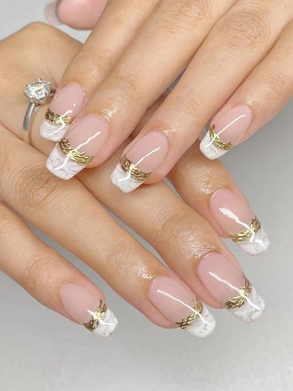 An elegant French manicure on square nails with a white marble tip and a delicate gold leaf overlay.