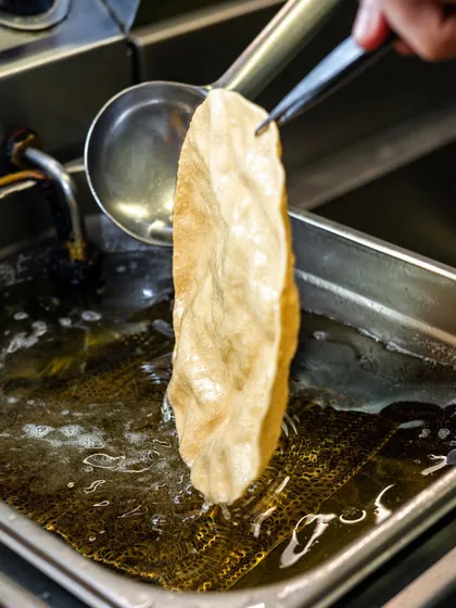 A crispy Kerala papad being lifted from the hot oil at Kari Apla. This shot captures a specific cultural dish in a dynamic way.