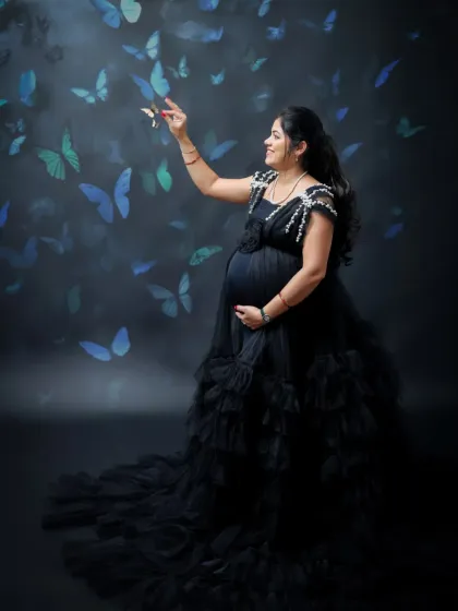 A magical solo portrait with a fantasy theme. The mom-to-be is surrounded by a swirl of blue butterflies, creating a dreamy and enchanting scene.