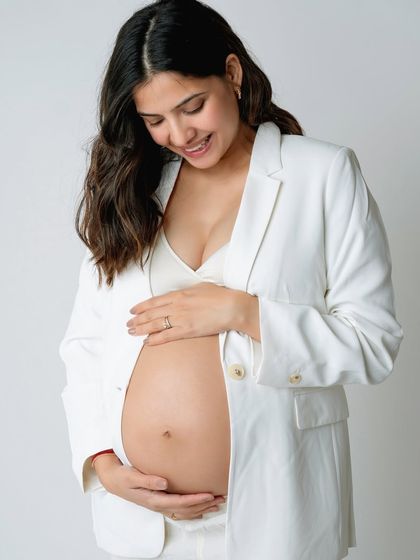 A close-up of a beautiful baby bump. The white blazer adds a touch of modern elegance to this maternity portrait.