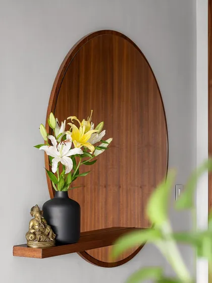 The foyer in our 'Gulmohar' project features this unique oval wooden mirror with an integrated shelf, creating an auspicious and warm welcome.
