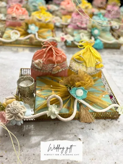 A beautiful wedding gift arrangement featuring colorful potlis and a decorated gift box on a golden tray. This is a perfect example of how I create vibrant and traditional return favors for wedding guests.