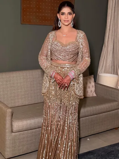 The full-length view shows how the dramatic high ponytail complements the shimmering, modern ethnic outfit perfectly.