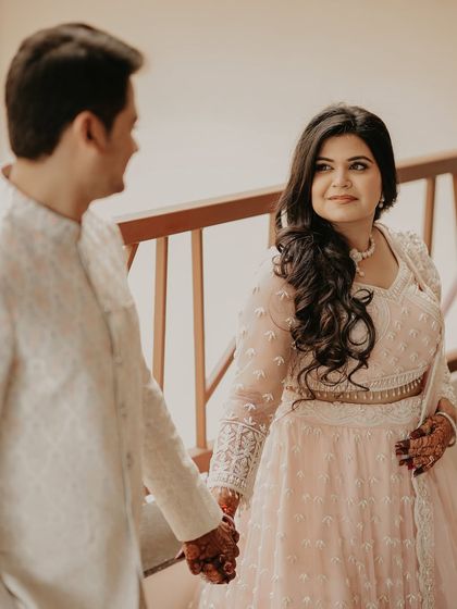 A candid, over-the-shoulder shot capturing the bride's loving gaze. This intimate moment highlights her beautiful pastel lehenga and the couple's easy connection.