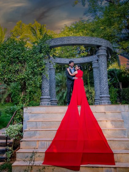 This epic shot shows the full length of the red flying gown's trail, creating a stunning visual on the steps of this monument. It's a perfect example of a dramatic pre-wedding photo.