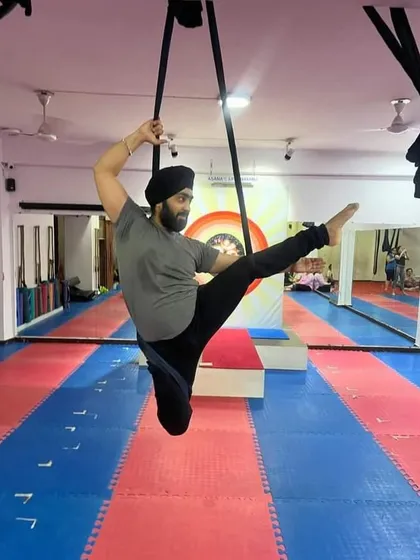 Aerial yoga is for everyone. Here, a student demonstrates a seated pose within the hammock, working on hip flexibility and balance with a unique challenge.