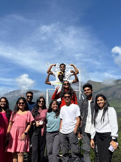 A fun group photo with the stunning mountains of Munnar in the background.