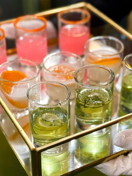 A server presents a tray of colourful welcome drinks. These small glasses of refreshing mocktails are the perfect way to greet guests as they arrive at an event.