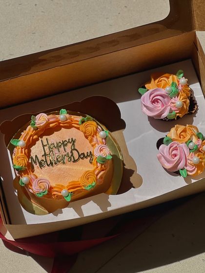 A Mother's Day gift box with a bento cake and two matching floral cupcakes.