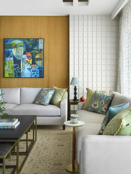 A wider shot of the living area, showing the comfortable L-shaped sofa, nested coffee tables, and the vibrant artwork that serves as a focal point.