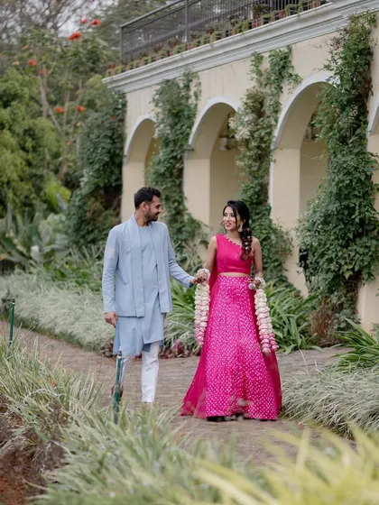 A couple walking hand-in-hand through the beautiful gardens of Sula Vineyards. This shot captures a relaxed moment against a lush, scenic backdrop.