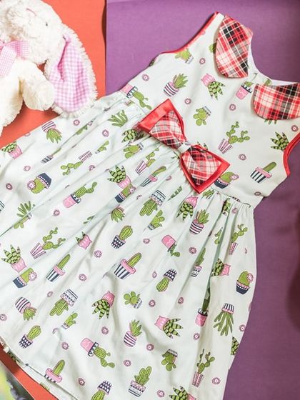 A flat-lay of a fun cactus-print dress, surrounded by a ukulele and a stuffed bunny. It shows the playful and imaginative world that my dresses are a part of.